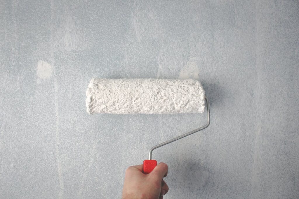 Person holding paint roller on the wall