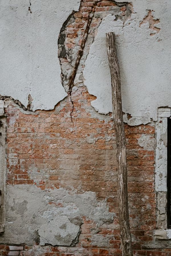 A damaged old brick wall with concrete patches.