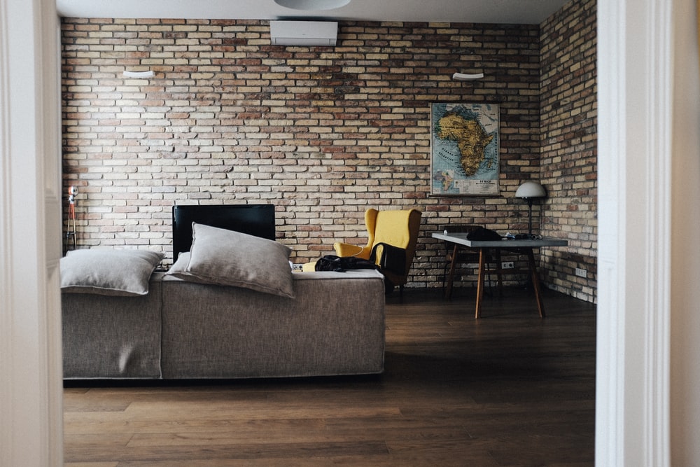 a bricked room with gray sofas