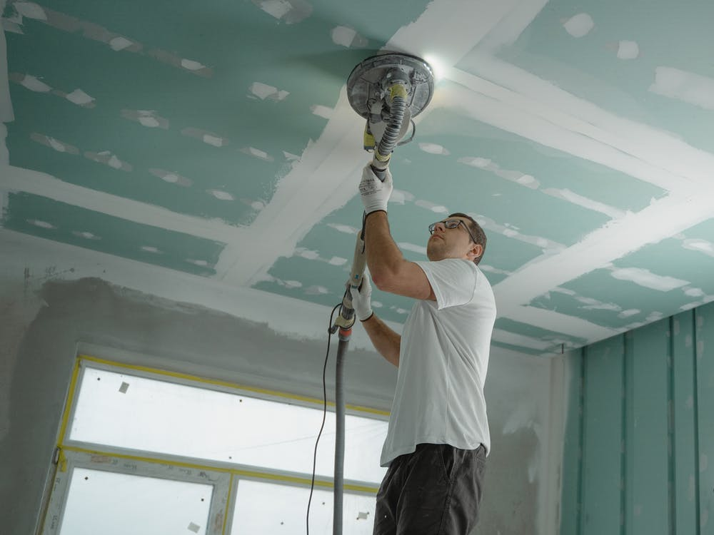 A man in a white shirt polishing the ceiling.