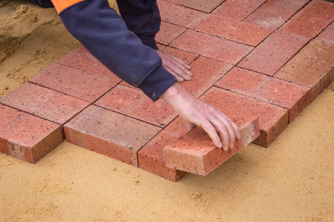 Man placing bricks on the ground.
