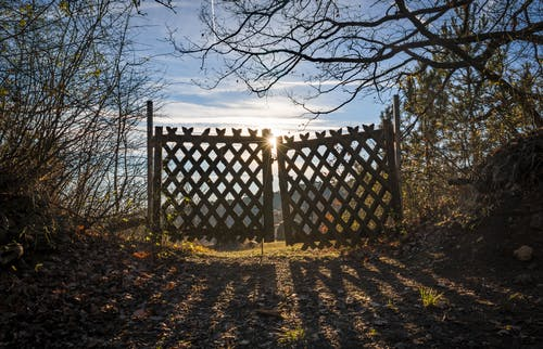  a simple and rustic swinging wooden gate installed at a muddy pathway