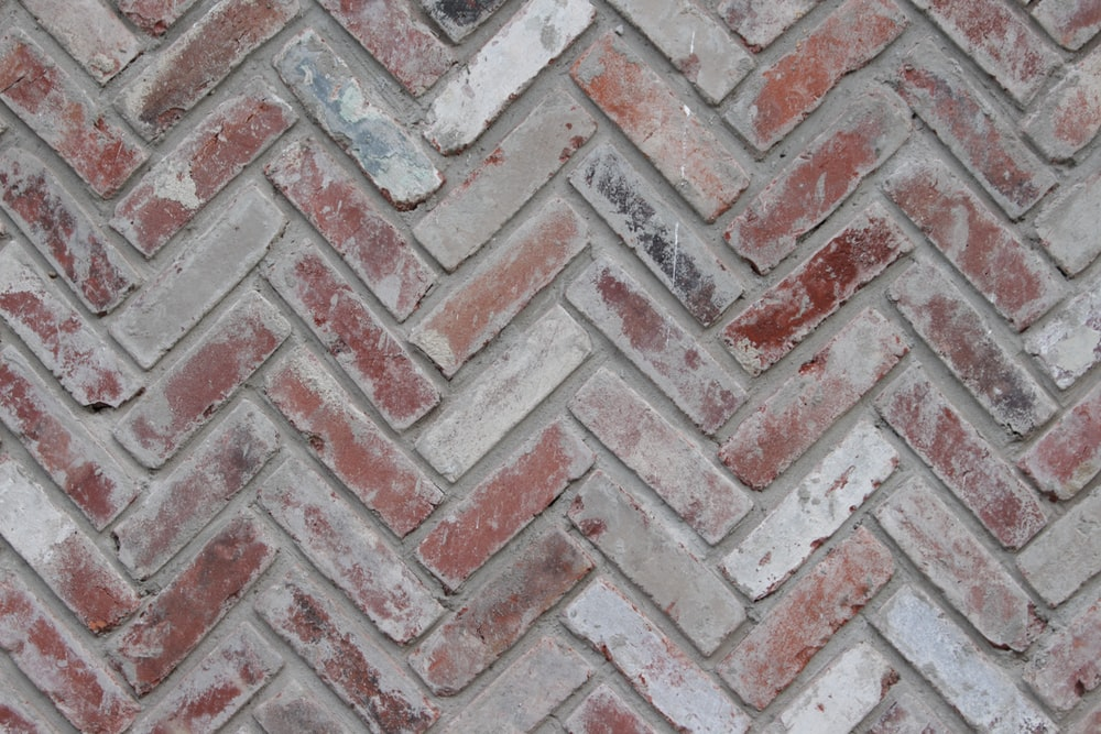 a wall made up of bricks placed in a V-pattern and covered in white mortar paste