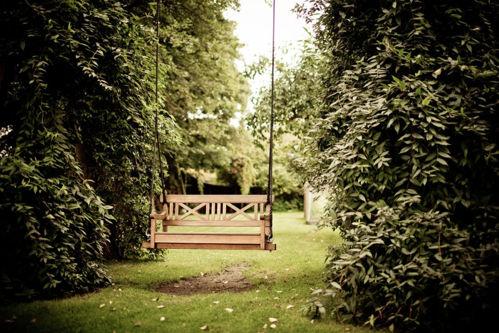 A garden with a wooden swing.