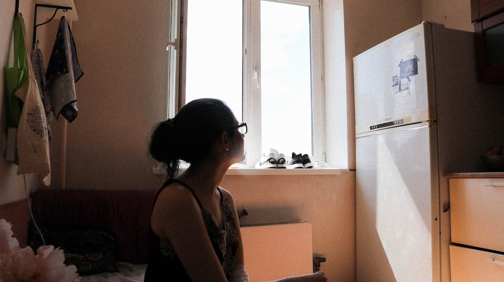  a woman staring at a refrigerator